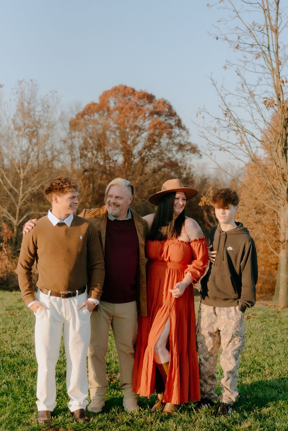 Group portrait of family members in coordinated autumn colors standing in a field.