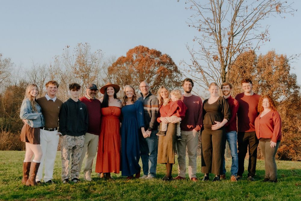Extended family gathered outdoors for a group photo on a sunny fall day.