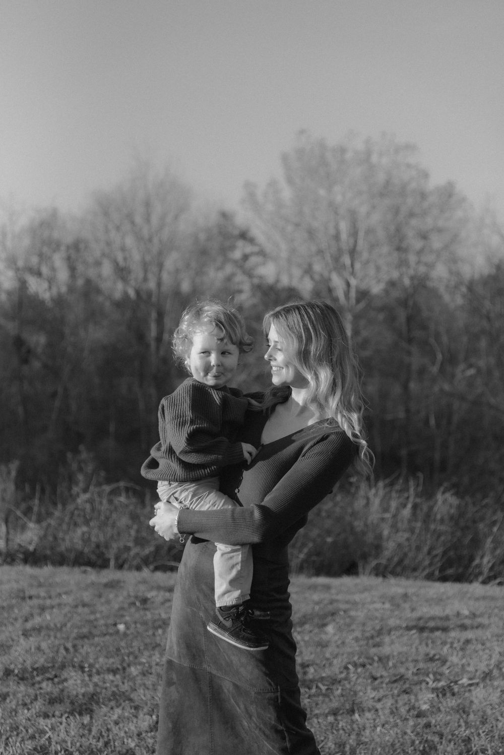 Black and white photo capturing a tender embrace between parent and child outdoors.