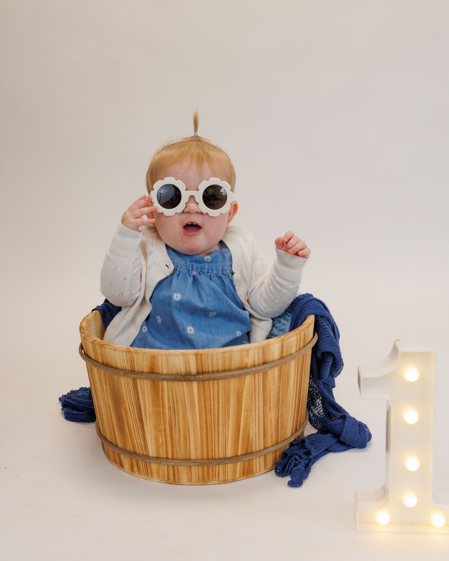 First birthday session for a little boy on a plain background and neutral colors in a cozy studio in Attica, Michigan.