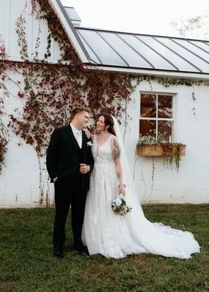 Elegant wedding couple shares romantic moments against white greenhouse walls with climbing vines in fall setting.