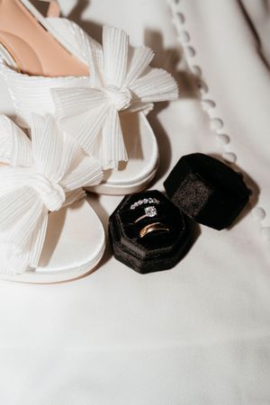 Elegant white ribbon bows displayed alongside black velvet ring boxes on a light surface.