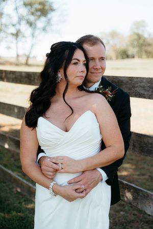 A romantic wedding photo series showing close embraces against a rustic wooden fence in natural outdoor lighting.