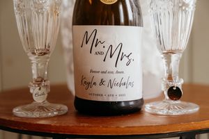 Elegant wine glasses and personalized wedding favors arranged on a wooden table at a reception celebration.