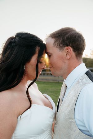 A tender wedding moment captured at sunset with the couple sharing an intimate kiss.