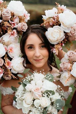 A romantic wedding portrait featuring delicate pink and white roses framing a bouquet of blush and cream florals.