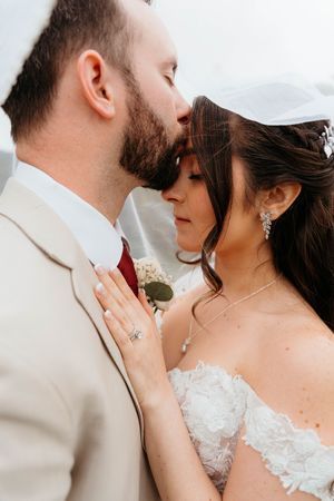 Close-up romantic moment between couple in wedding attire with soft lighting.