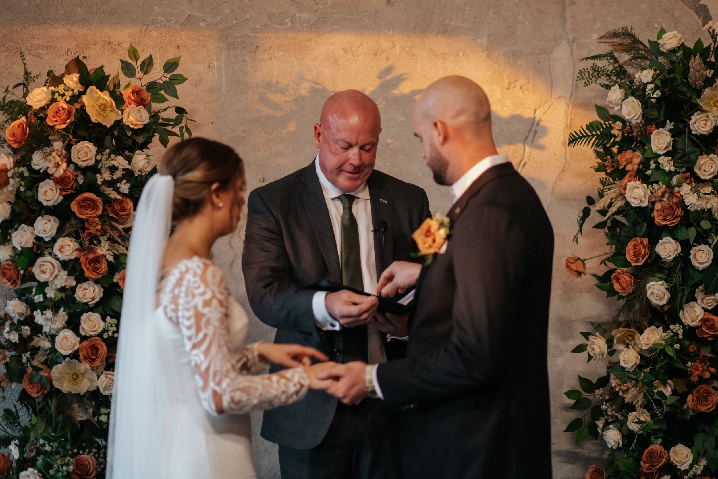Wedding ceremony with floral arrangements and warm lighting in an industrial-style venue.