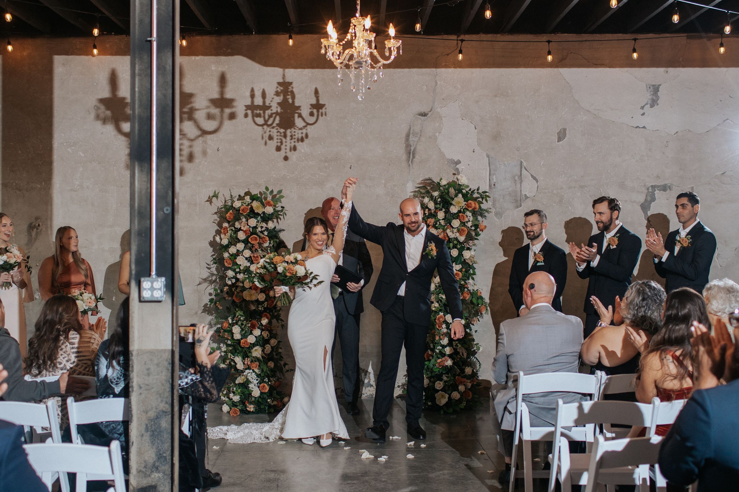 Wedding celebration in an industrial venue with exposed brick walls and elegant chandeliers.