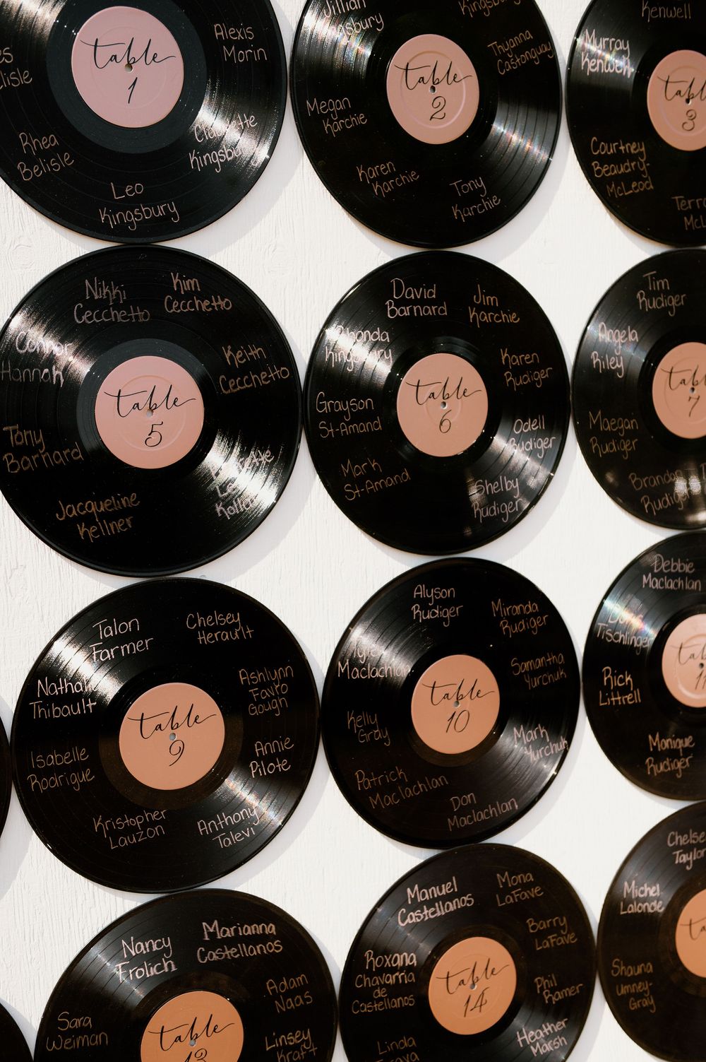 Vintage vinyl records arranged in a pattern with table numbers written in rose gold.