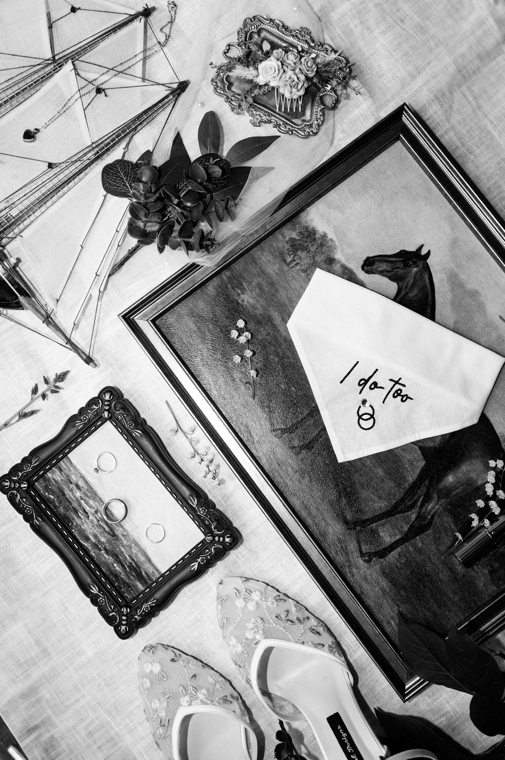 Black and white flatlay of wedding details including handwritten notes and vintage frames.