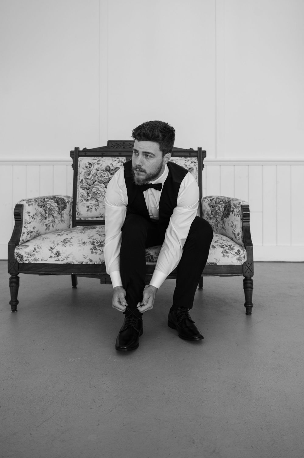 A formal portrait series on a vintage floral settee against a white backdrop.