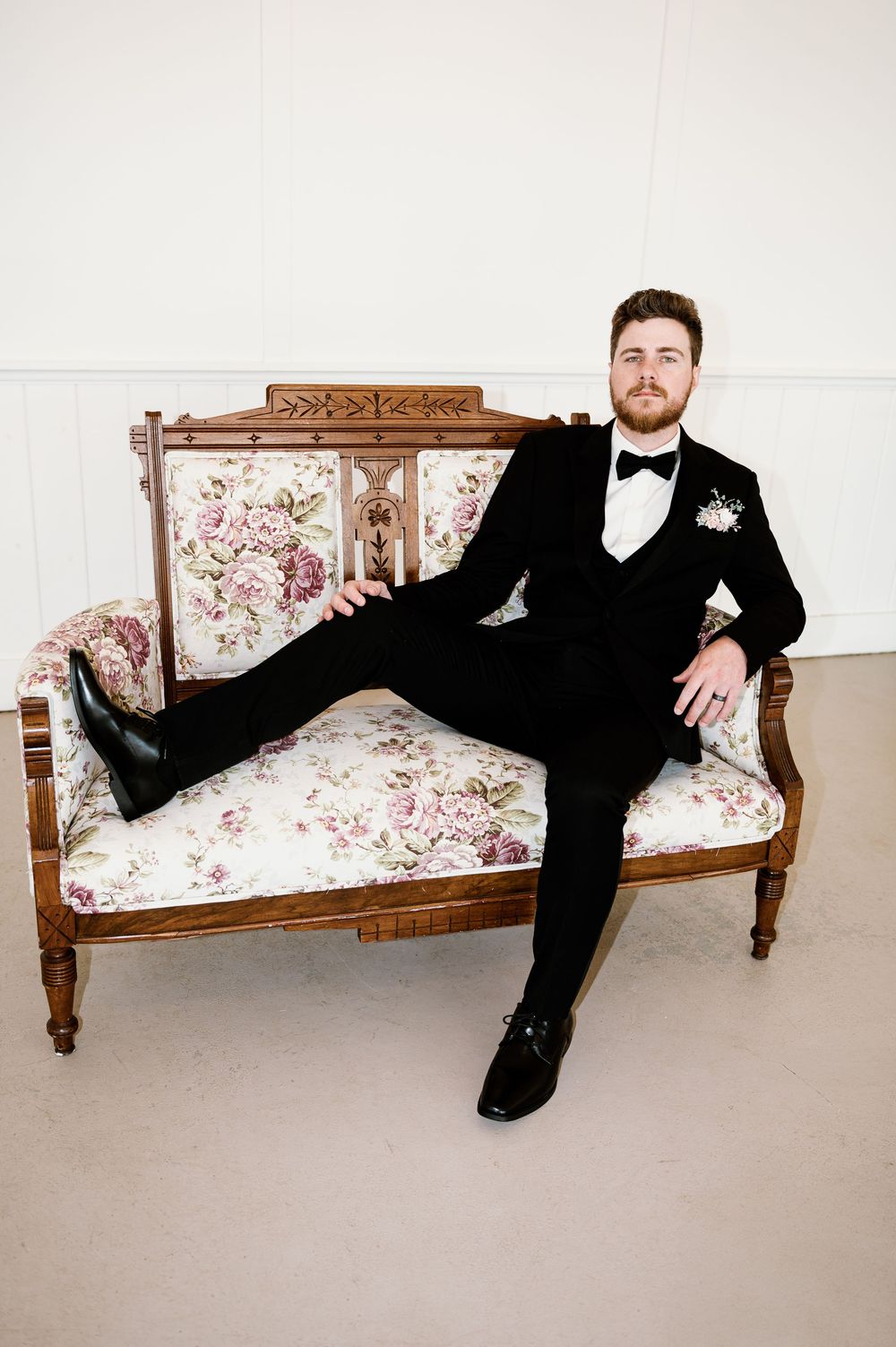 Stylish poses on a vintage floral settee showing relaxed formal attire and artistic composition.