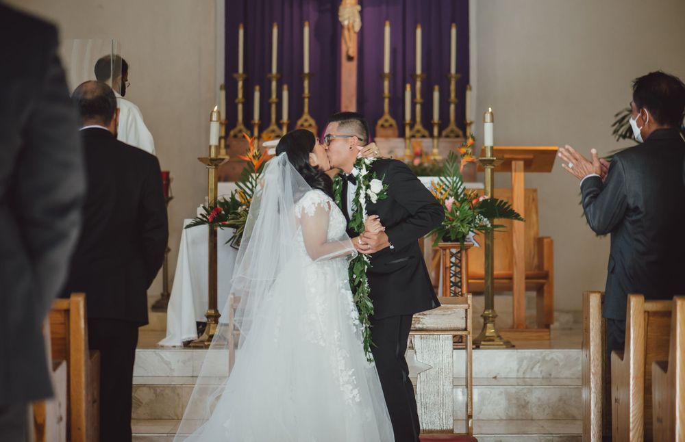 Wedding ceremony in purple-lit church with traditional decor and candles.