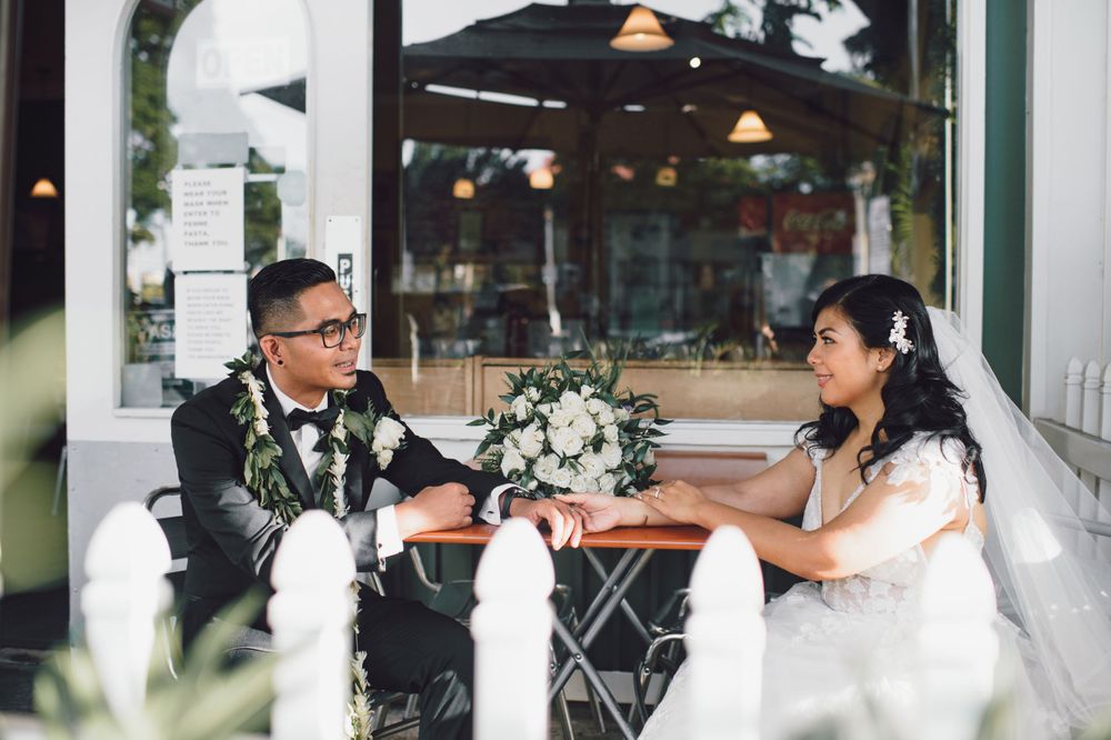 Intimate wedding couple portrait against white architectural backdrop.