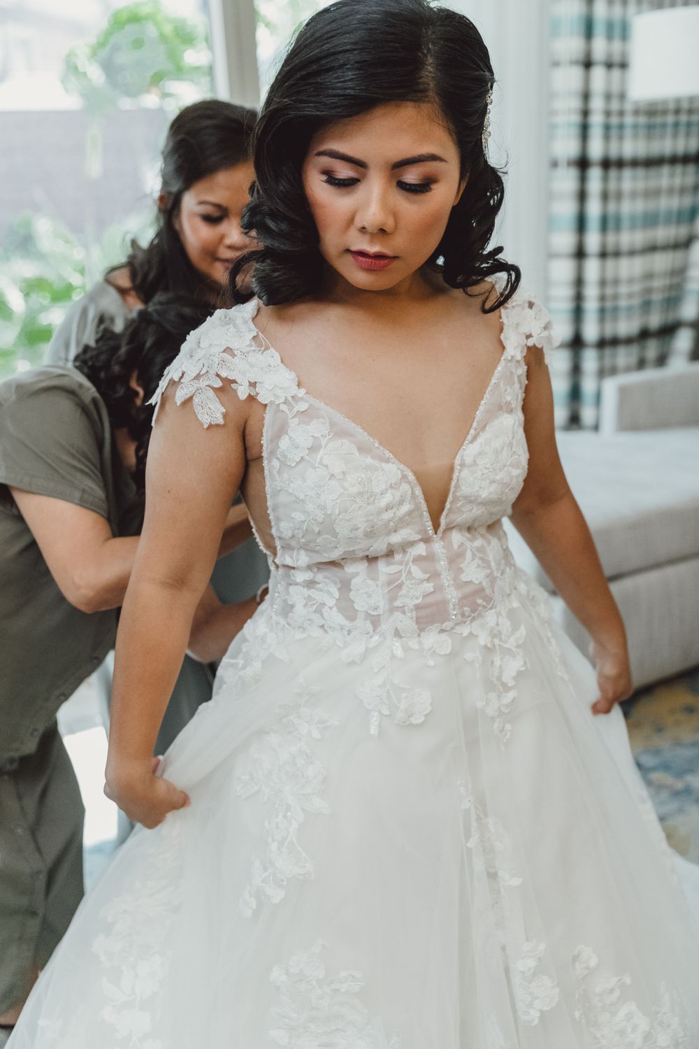 Final wedding dress adjustments showing intricate lace details and plunging neckline.