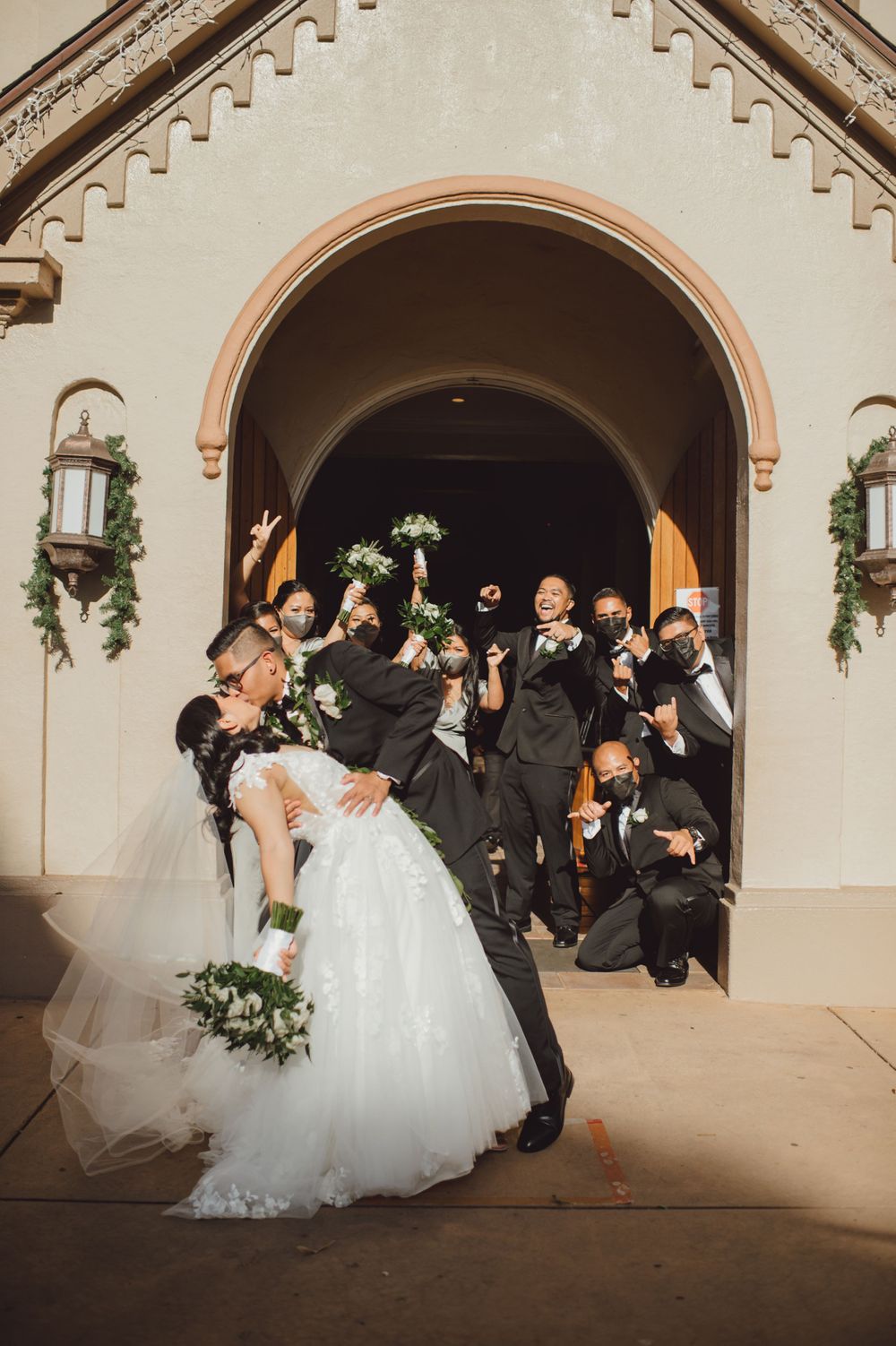 Wedding party poses under arched doorway for creative group photo.