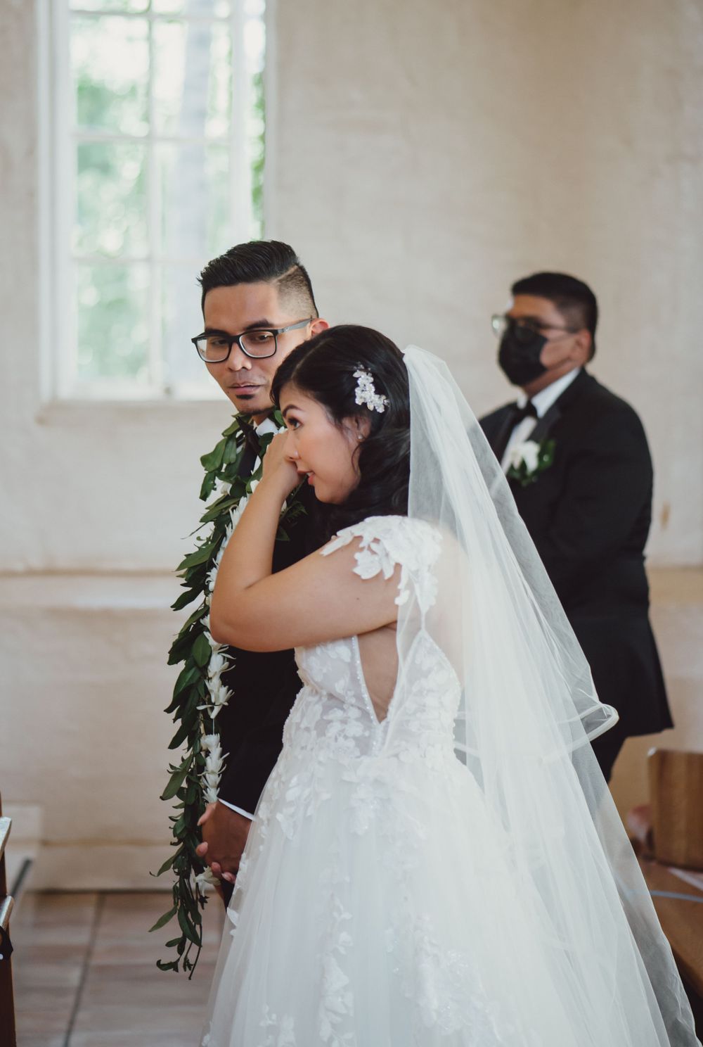 Emotional first look moment in bright church venue with flowing white wedding dress.