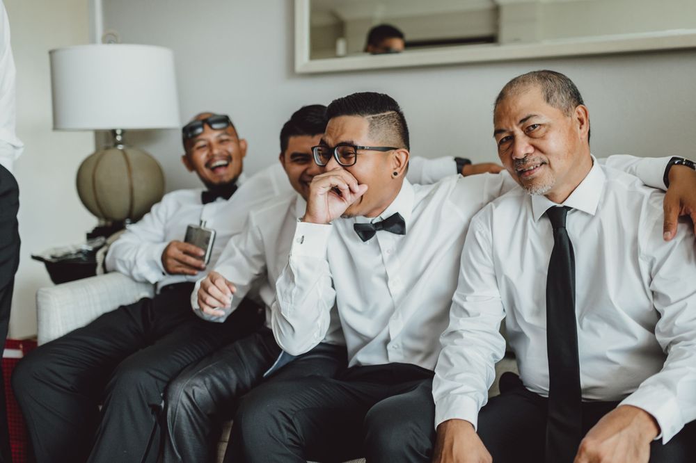 Wedding party members in white shirts and bowties share emotional reactions.