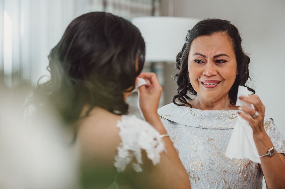 Bride in white dress reads letter with joyful expression during wedding preparation.