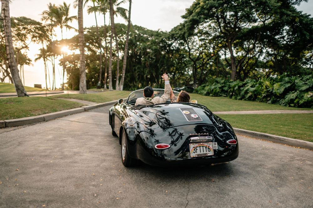 Sleek vintage convertible parked on a coastal road during golden hour.