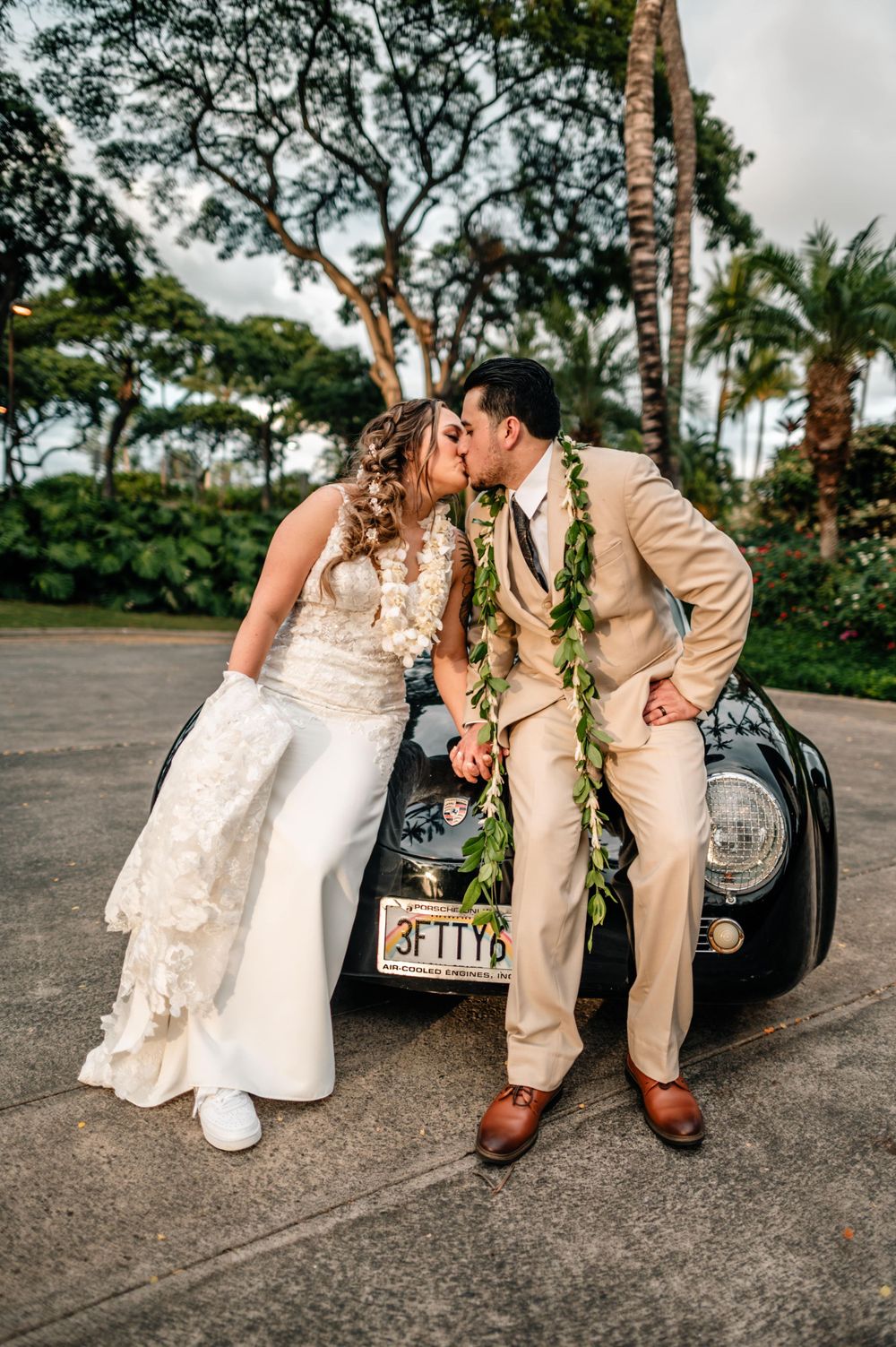 Wedding couple poses with vintage car showing beautiful lace dress details.