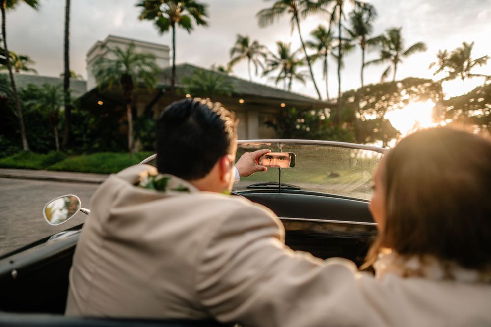 Sunset silhouettes of wedding couple against tropical palm tree landscape.