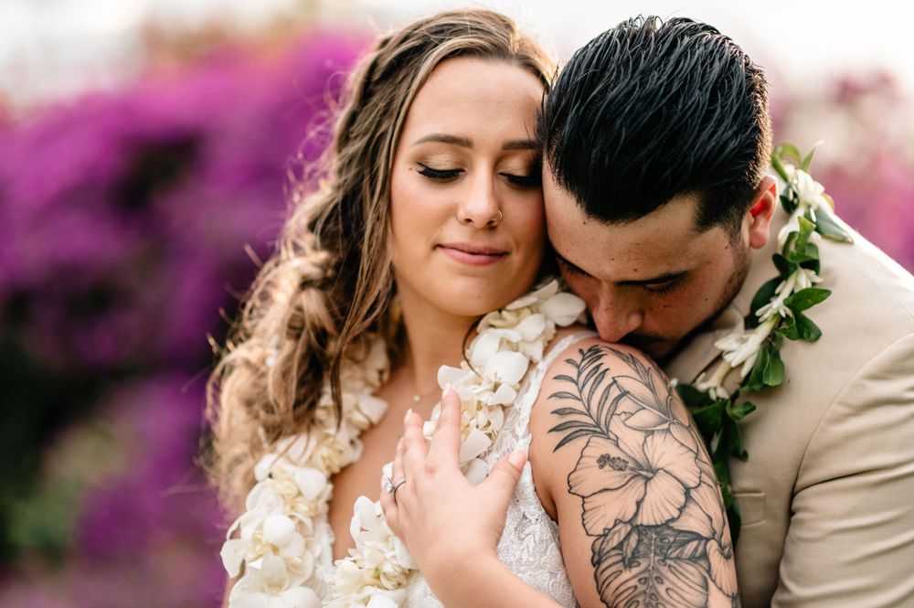 Tender moments between newlyweds surrounded by purple flowering bushes.