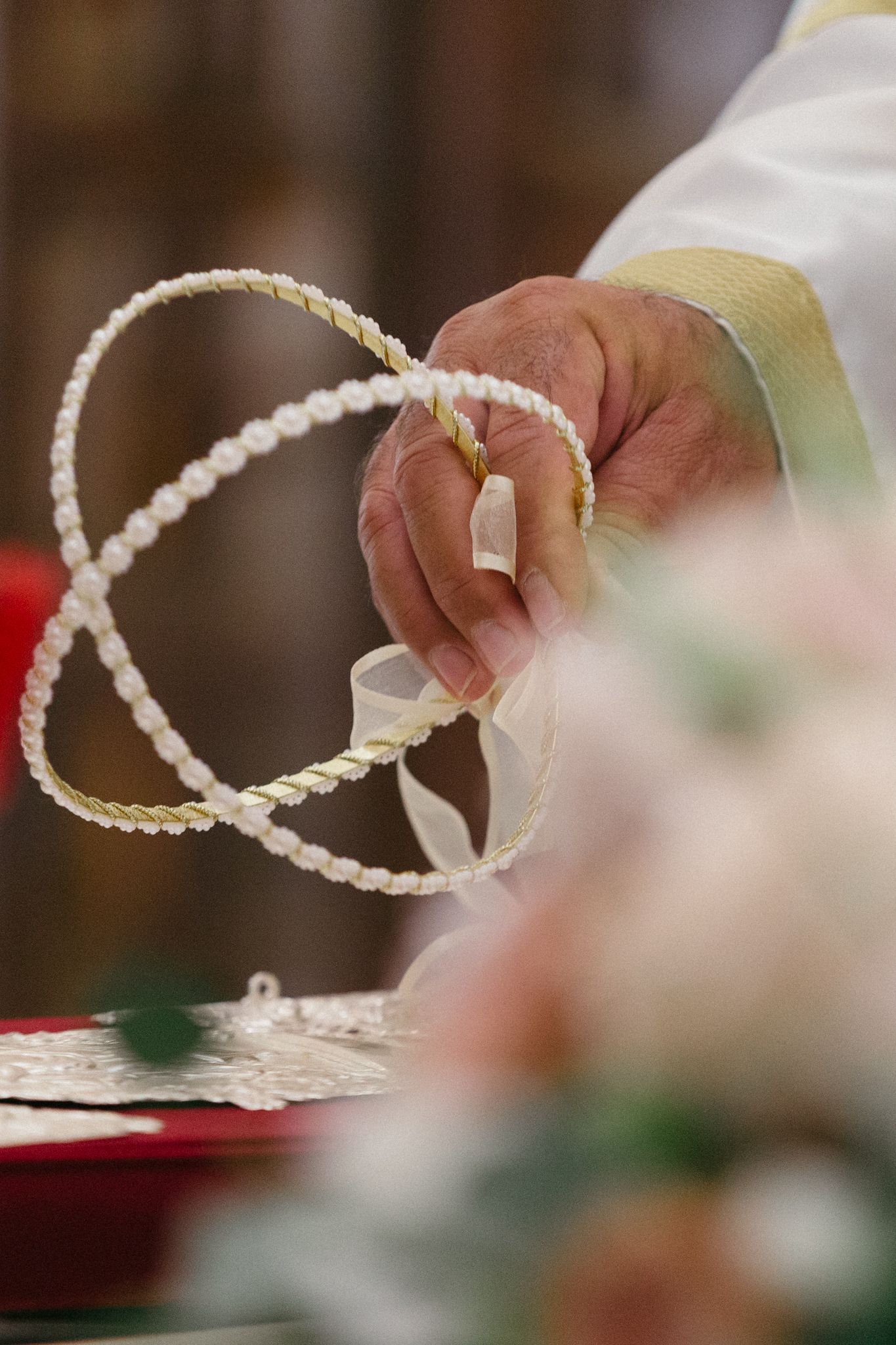 Hands delicately hold a white decorative rope or cord trim against a blurred background.