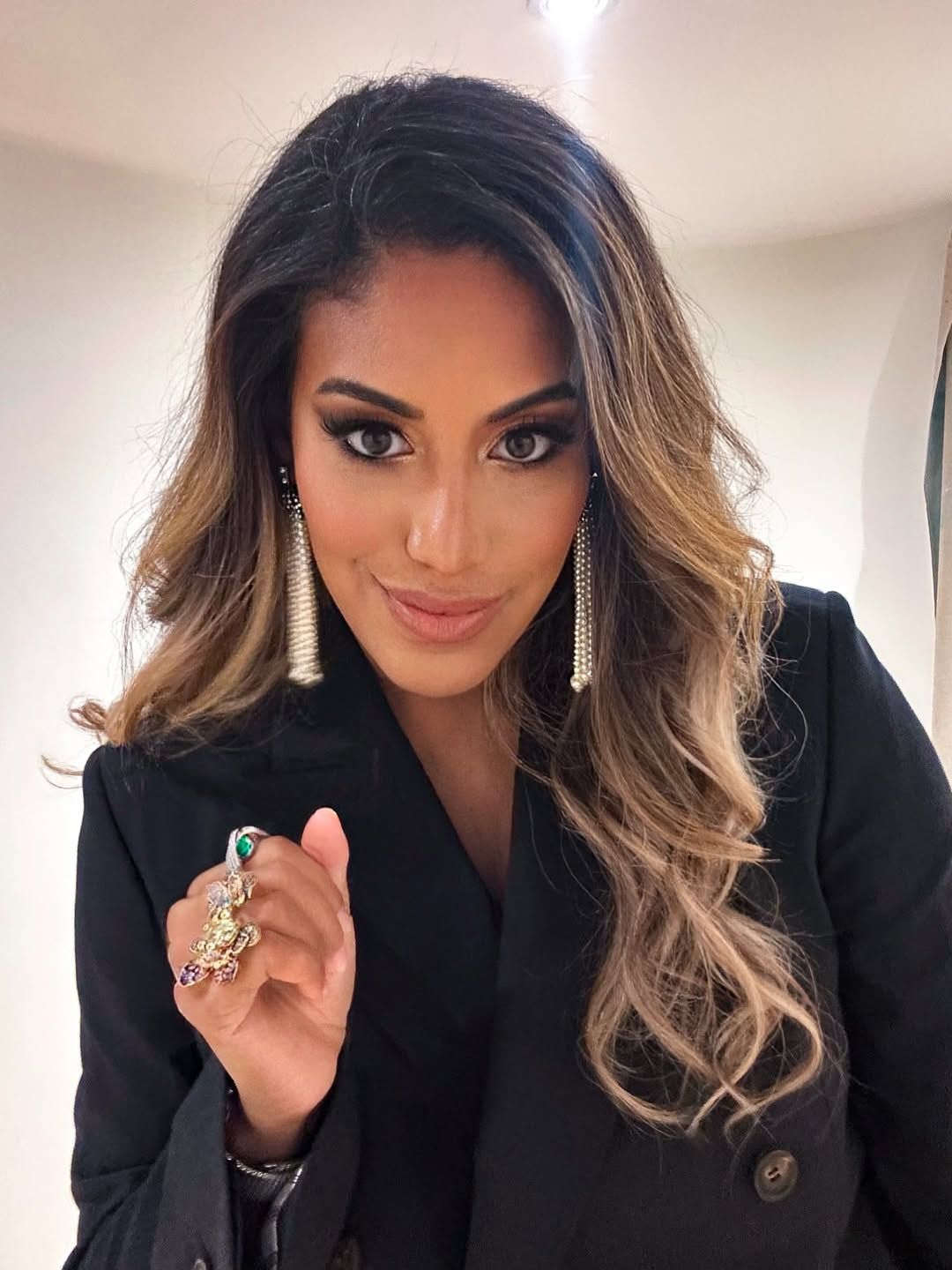 A woman in a black blazer poses with ombre hair and statement earrings in a series of selfie photos.