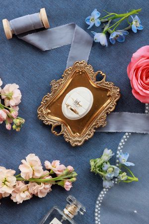 Vintage gold ornate frames with pearl necklaces and delicate pink and blue flowers on dark gray background.