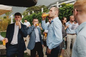 A group of well-dressed men in suits and formal attire enjoying drinks together at a wedding cocktail in lisbon