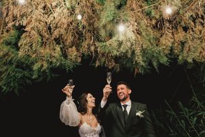 A couple dances and embraces under twinkling string lights and tree branches at an outdoor evening wedding reception in Lisbon