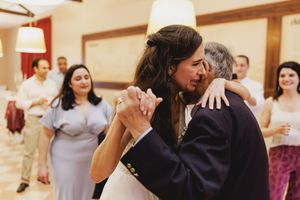 Bride and grandfather share an intimate dance together at a wedding reception while guests look on in the background