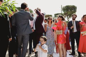 Wedding guests gather outdoors for a casual reception celebration in a garden setting.