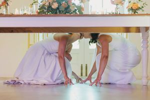 Two brides sharing a kiss under the dinner table during their wedding in Lisbon