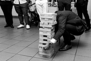 A group plays a large-scale Jenga game with wooden blocks on a tiled floor during a wedding in Lisbon