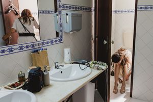 Bride getting ready in a modern bathroom interior with white tile walls and decorative blue border trim.