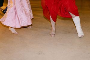 A group of people in red and pink formal dresses dance together at a wedding dancefloor.