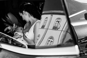 A black and white photograph of a bride breastfeeding her baby before a church ceremony in Lisbon