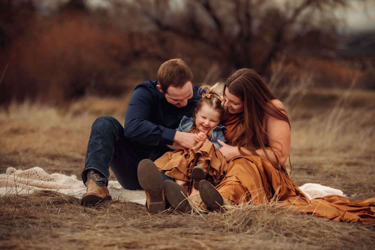 A couple lying in a rustic field with blankets during an intimate autumn photoshoot.