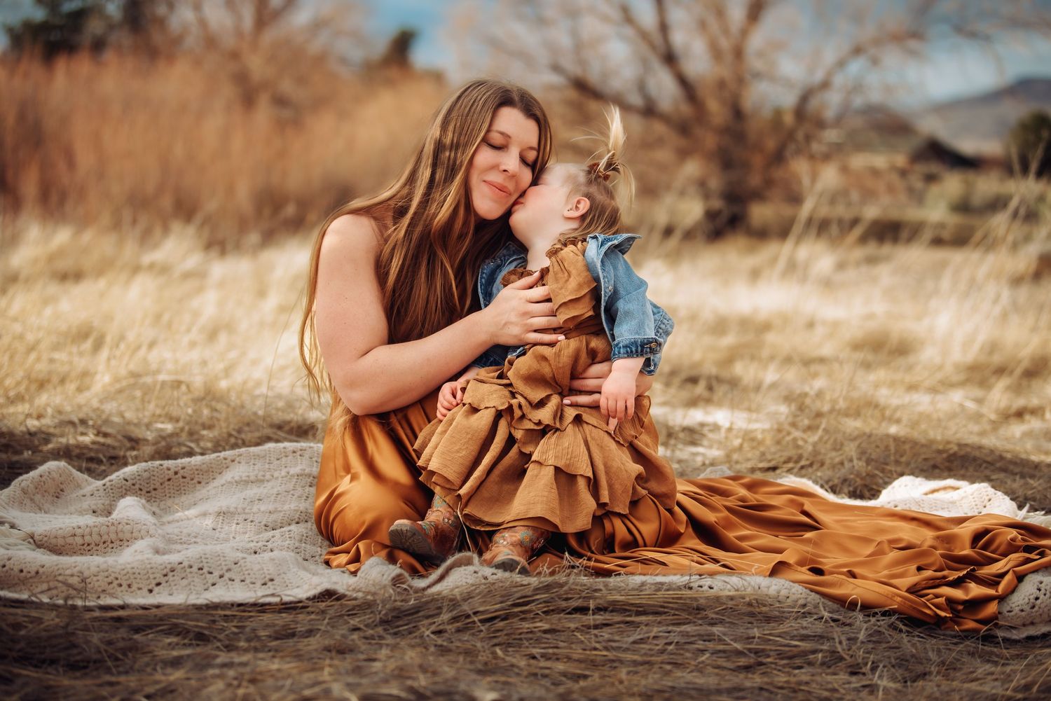 A rustic outdoor photoshoot featuring a flowing rust-colored dress against a golden field at sunset.