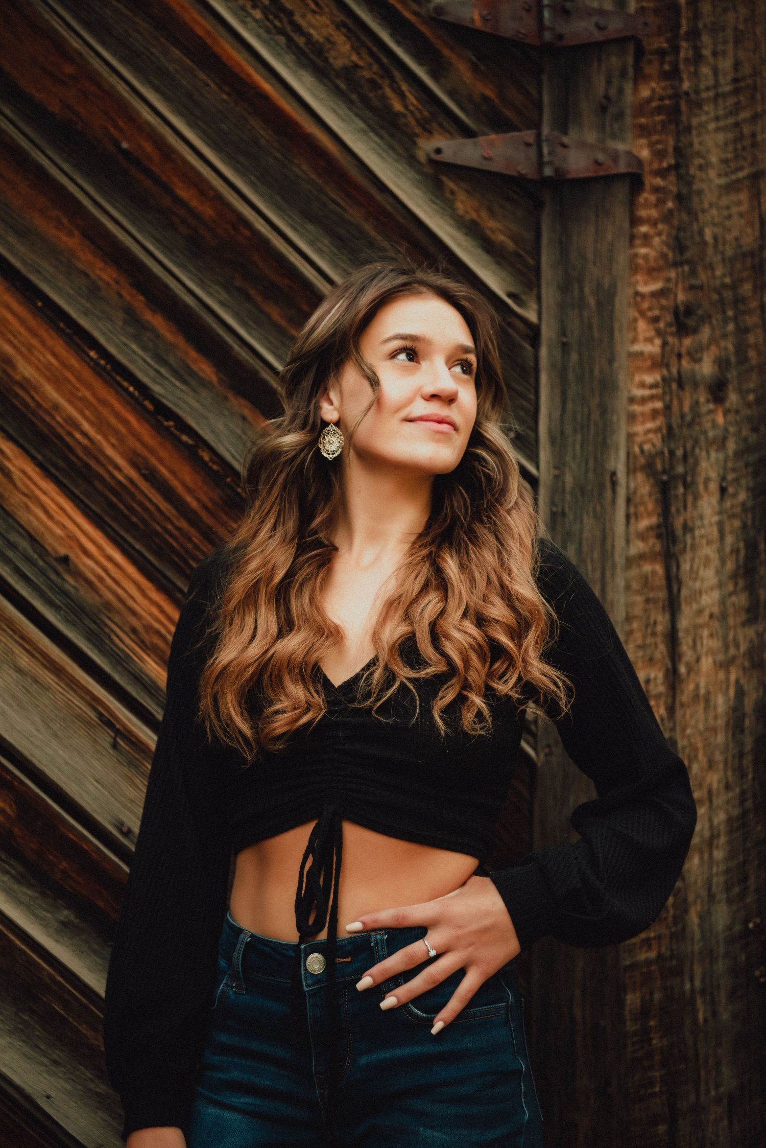 Portrait against rustic wooden wall showing casual style and natural lighting.
