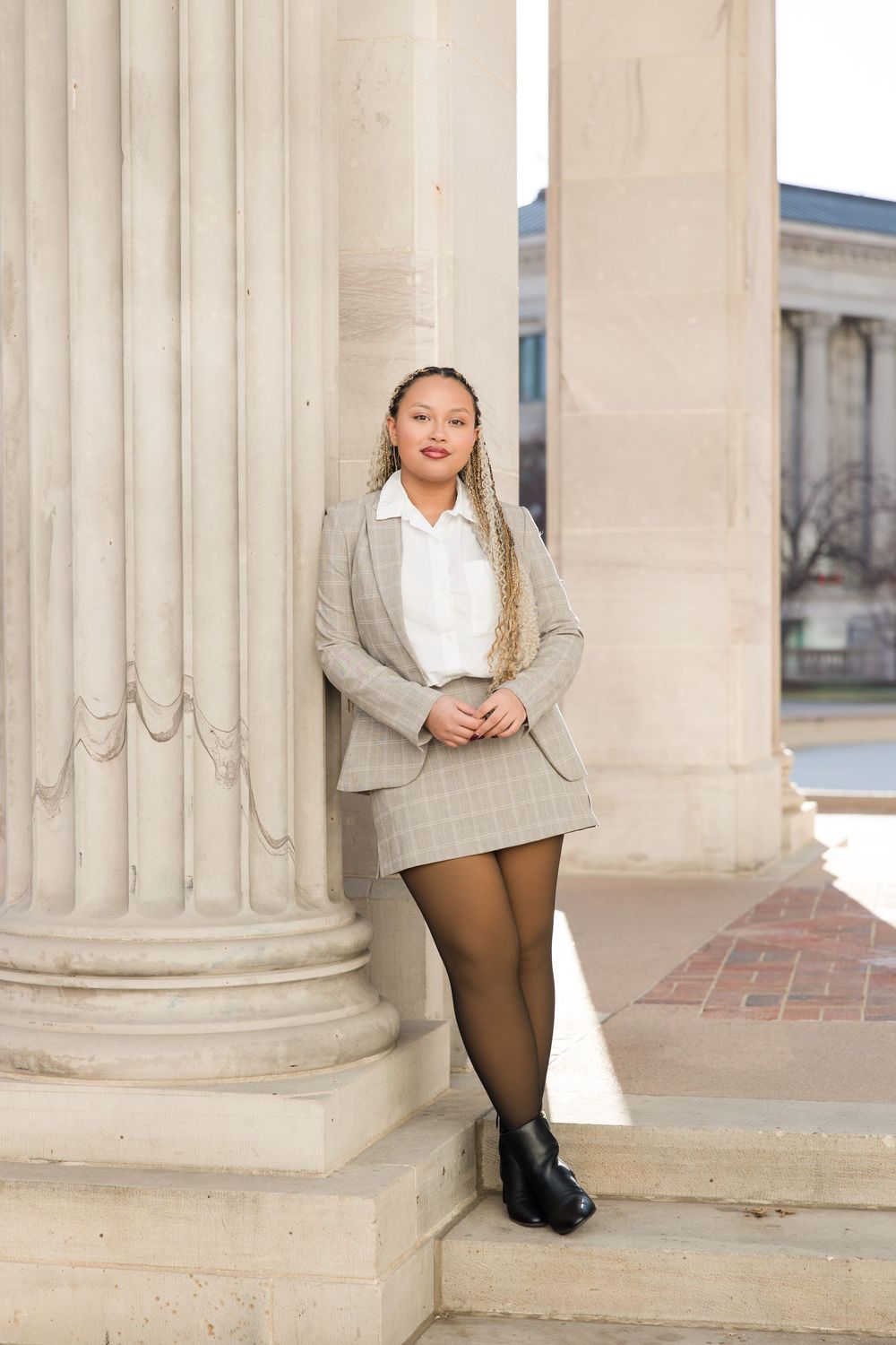 Stylish business attire photographed between elegant stone columns with natural lighting.