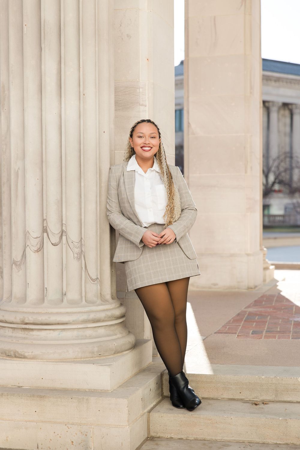 Professional portrait session featuring a grey plaid blazer and white shirt against classic stone columns.