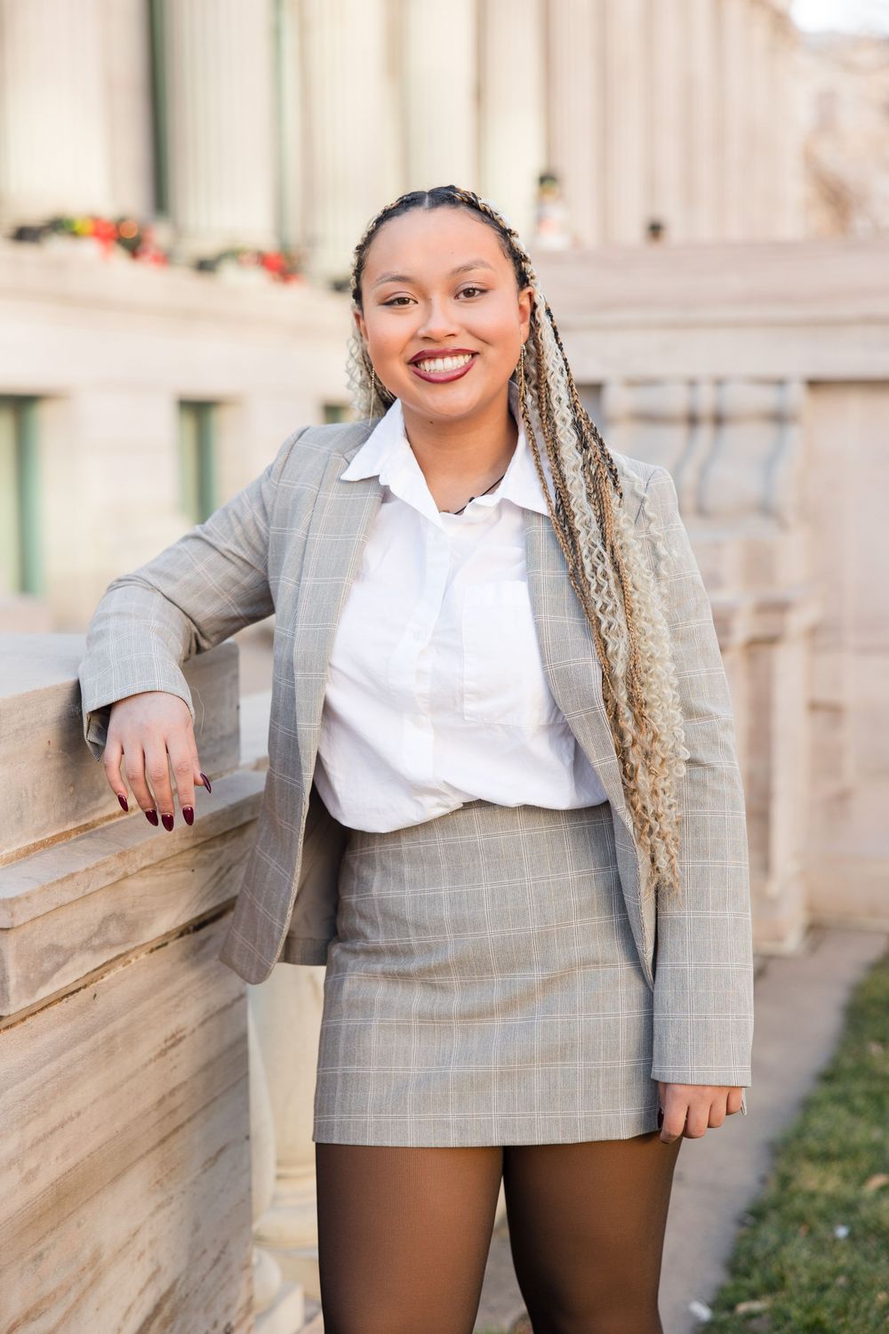 Business casual outfit with grey blazer and white button-up shirt photographed against stone architecture.