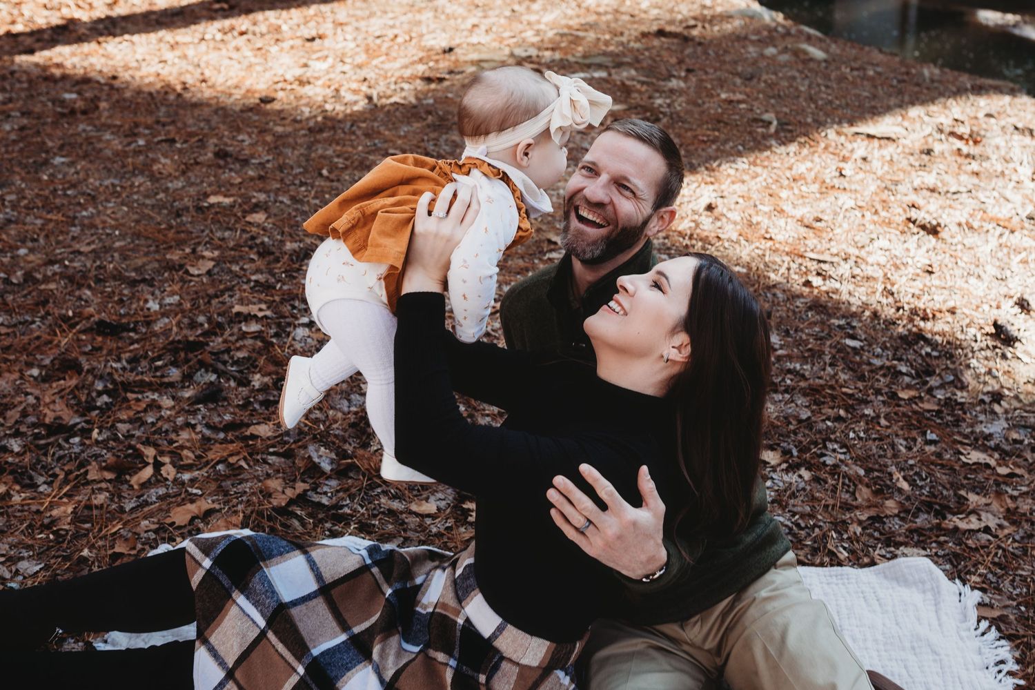 A couple sits together in a forest setting while sharing joyful moments together.