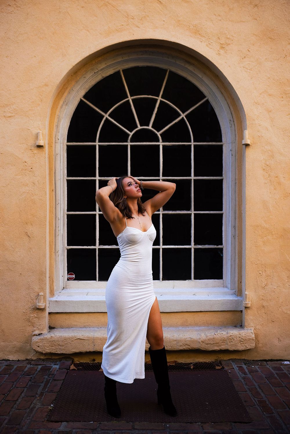 A person in a white tank top poses dramatically in a sequence of frames against a yellow wall with arched windows.