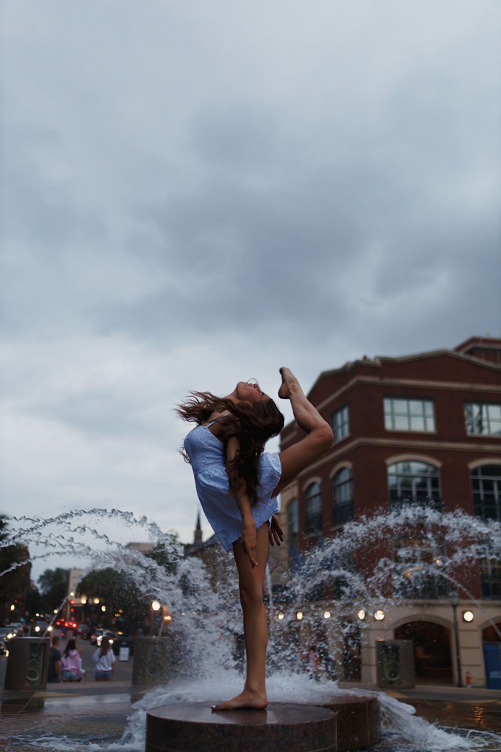 A sequence showing a person diving into a fountain at dusk with water splashing dramatically against city lights.
