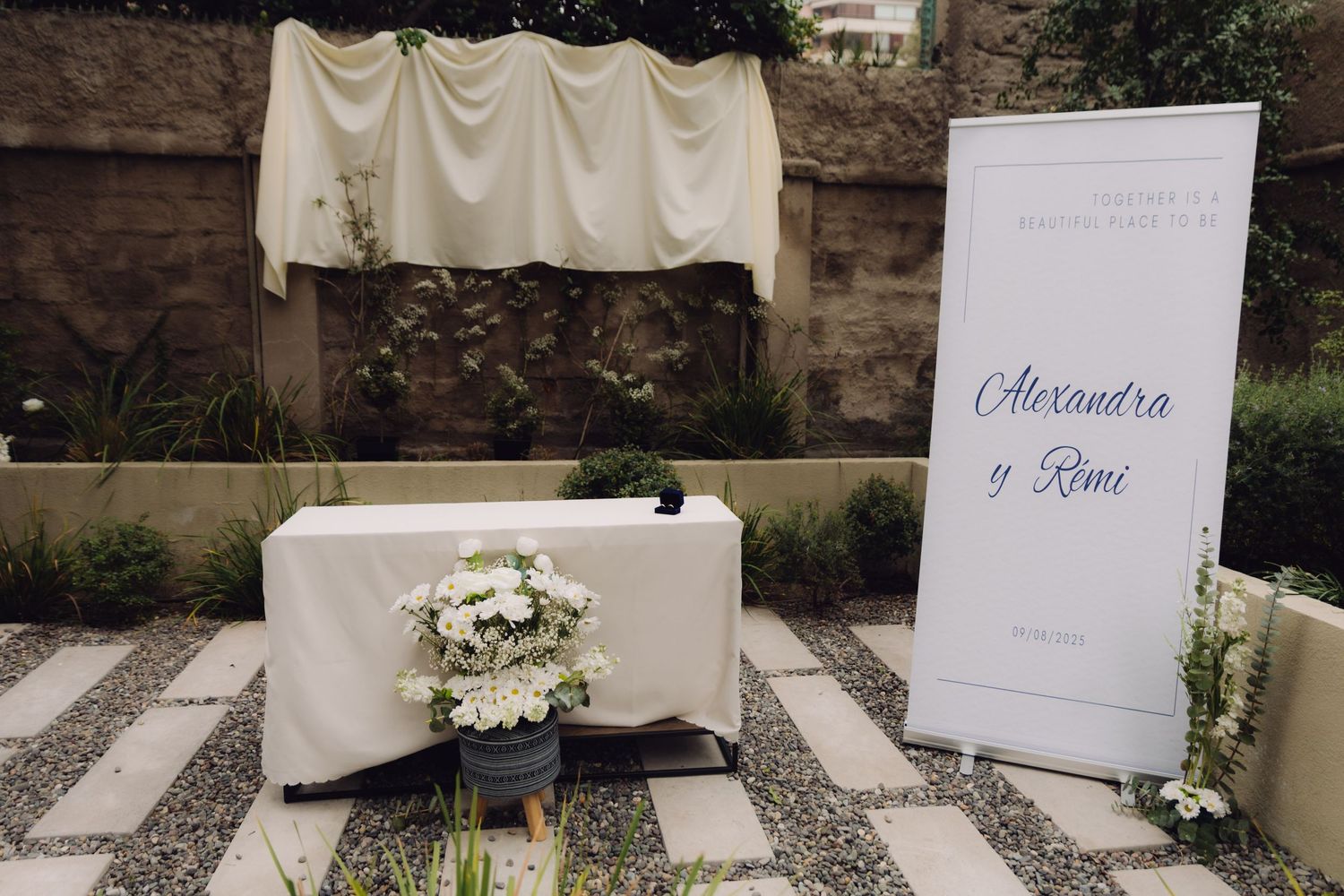 Outdoor wedding ceremony setup with Alexandra y Remi welcome sign and floral arch.